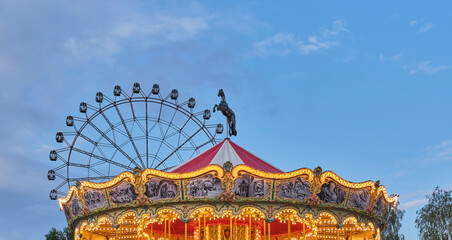 The dome of a children's carousel in a retro style. Evening amusement park.