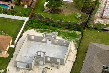 Aerial view of unfinished frame of private house with brick concrete walls ready for mounting wooden roof beams under construction