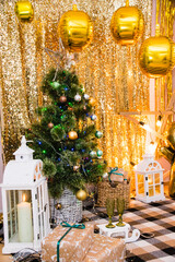 Christmas, New Year interior with golden balloons, garland and New Year decor and gifts under decorated Christmas tree