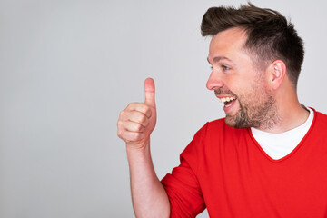 Attractive cheerful young man showing thumbs up