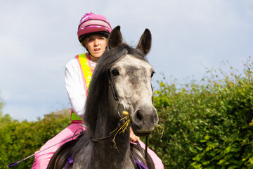 Obraz premium Close up shot of beautiful grey horse and her pretty young female rider as they enjoy riding freely in the English countryside on a summers day.