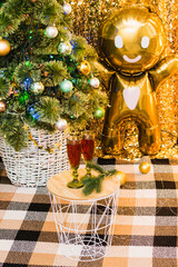 Concept of Christmas celebration and home comfort. Glasses with red wine on a table under a Christmas tree decorated with a garland and balls