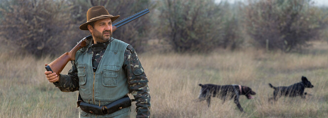 Hunter man in camouflage with a gun during the hunt in search of wild birds or game.