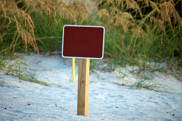 Empty signboard with copy space on seaside beach with small sand dunes and grassy vegetation on...
