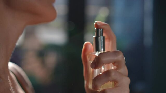 Close-up hand pressing cologne sprayer in slow motion spraying fragrance on female neck in slow motion. Side view closeup unrecognizable slim young Caucasian woman applying perfume