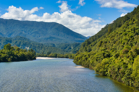 The Karamea River on the West Coast of South Island, New Zealand, flows through densely forested hills
