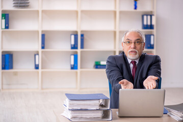 Old male employee sitting at workplace