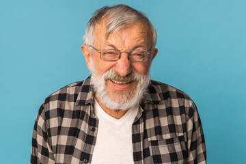 Close-up portrait retired old man with white hair and beard laughter excited over blue color background