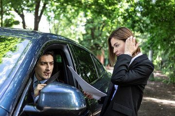 Young business people working together while traveling by a car. Attractive business woman standing close to the car and looking at the documents