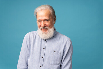 Retired old man with white hair and beard smiling excited over blue color background