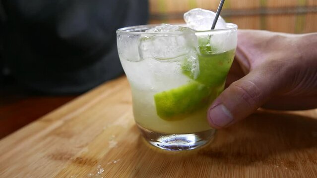 Mixing a caipirinha drink. Sugarcane liquor drink. Brazilian caipirinha made with cacha&ccedil;a and lemon. Caipira drink recipe.
