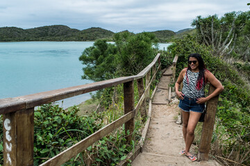 Naklejka premium Mulher em ponte de madeira perto do Forte São Mateus em Cabo Frio, apreciando a linda paisagem.