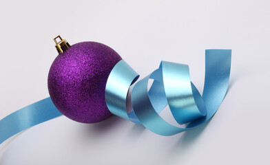 Close-up Violet glitter texture nacre and glow Merry Christmas ball, blue ribbon on beige...
