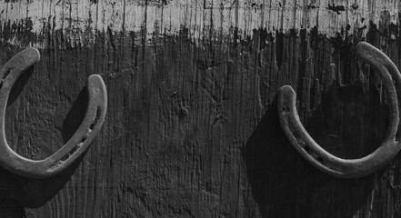 Western industry background with room for text between horseshoes on wood texture in black and white.