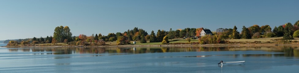 Obraz premium Panoramic shot of a rural coastal village on the bank of a lake with autumn trees in New England,USA