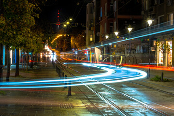 Night scene of tram in traffic at crossing with lighttrail motion blur