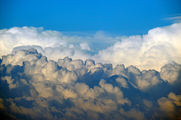 White fluffy cumulonimbus clouds forming before thunderstorm on summer blue sky. Changing stormy...