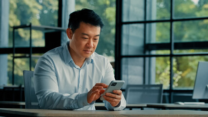 Excited surprised winner businessman successful mature asian japanese korean chinese man win surprise profitable offer online betting reading good notification on mobile phone rejoice business success