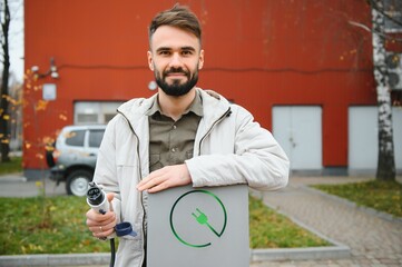 Man hand holding Electric car charger. Electric Vehicle EV Charging station and Charger.