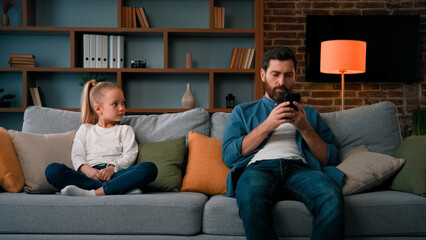 Bored child girl resting at home with father young dad using mobile phone little kid need attention looking at daddy taking modern gadget young family generation internet technology addiction concept - obrazy, fototapety, plakaty