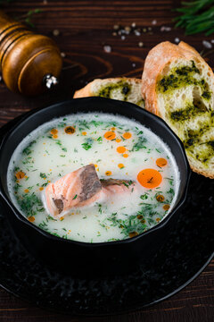Finnish fish soup with salmon, cream, potatoes, dill and bread with sauce and spices, closeup.