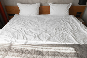 Fototapeta na wymiar Wide empty bed with wooden headboard two white pillows