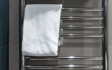 White towel hangs on a heated towel rail in the bathroom