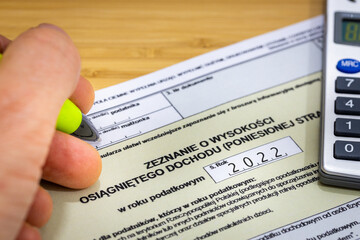 Hand of a person filling in the annual tax return to the tax office in Poland in 2023, Form for settlements for individuals for 2022 - obrazy, fototapety, plakaty