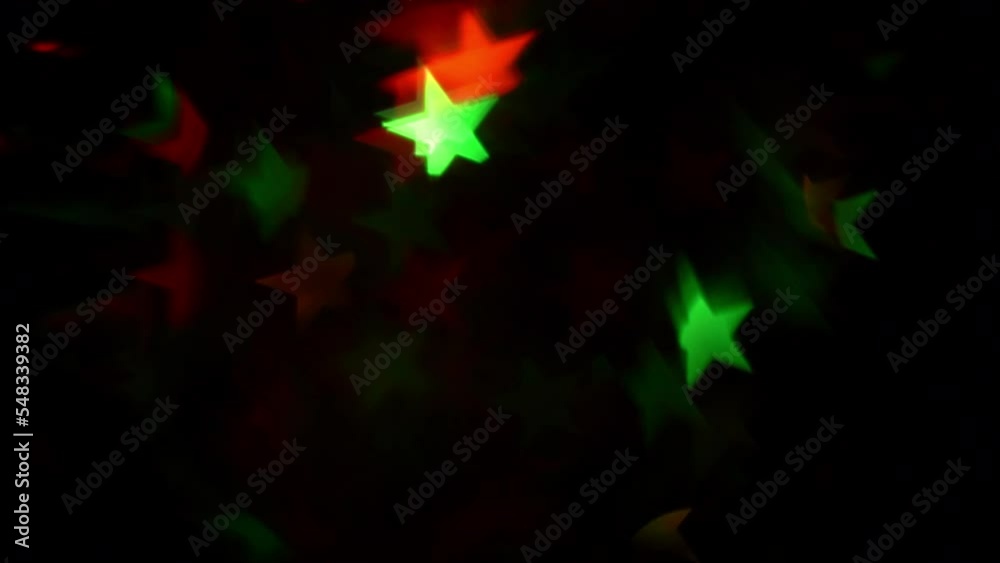 Wall mural abstract background of christmas bokeh stars. red and green stars flicker and fading on a black back