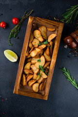 Baked rustic potato wedges with salt on a wooden board.