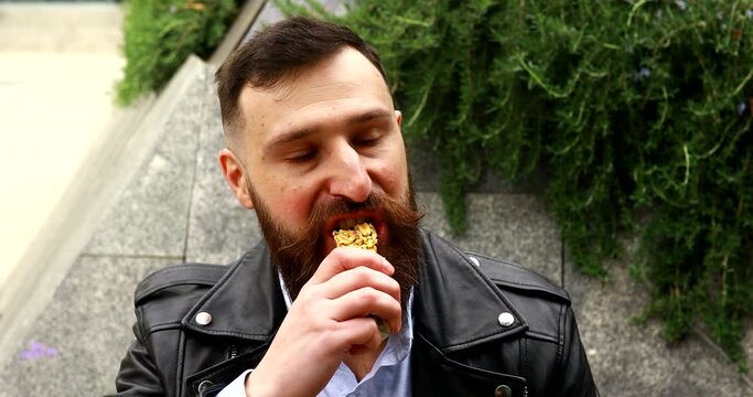 Happy bearded man eats snack bar. The bearded man smiling and posing with chocolate in hand.