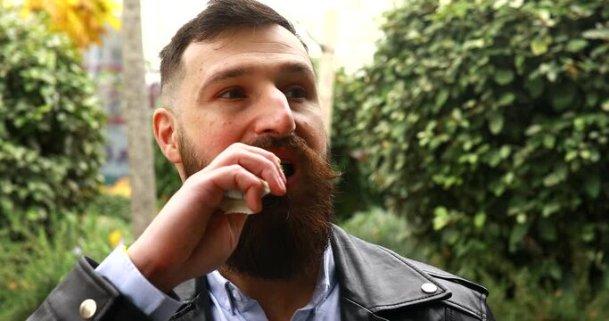Happy bearded man eats snack bar. The bearded man smiling and posing with chocolate in hand.