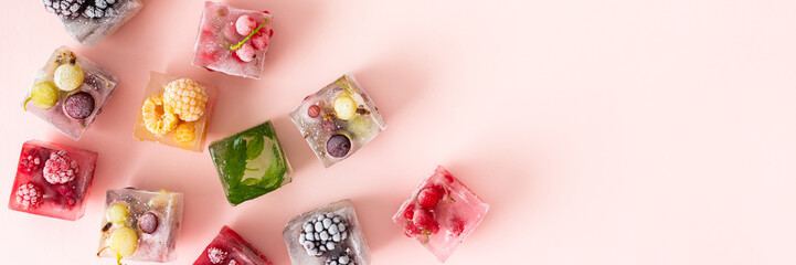Frozen ice cubes with various fruits banner, blackberries and raspberries, gooseberries and currants, blueberries and mint, top view