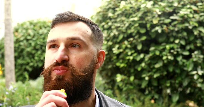 Happy bearded man eats snack bar. The bearded man smiling and posing with chocolate in hand.