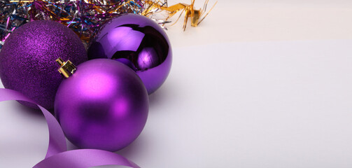 Close-up Violet glitter texture nacre and glow Merry Christmas ball, ribbon on beige background.