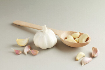 Fresh white unpeeled head bulb of garlic and garlic cloves on white grey color background with wooden spoon. Vegan, organic, vitamins. Natural antibiotic, antioxidant, Allicin. 