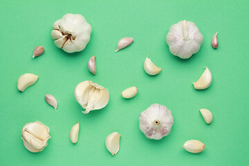 Fresh white unpeeled head bulb of garlic and garlic cloves on green color background. Vegan, organic, vitamins. Natural antibiotic, antioxidant, Allicin. Top view. Flat lay