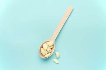 Fresh white garlic cloves on wooden spoon on blue color background. Vegan, organic, vitamins. Natural antibiotic, antioxidant, Allicin. Top view. Flat lay. Copy space for text