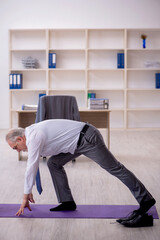 Old male employee doing sport exercises during break