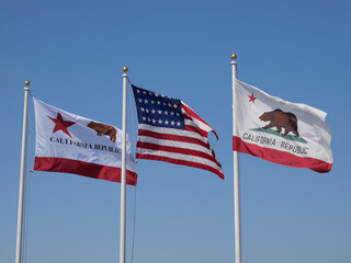 Flags of California and the United States of America against a clear blue sky