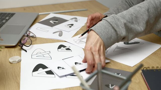 A graphic designer develops a logo for a brand. The illustrator draws sketches on paper.