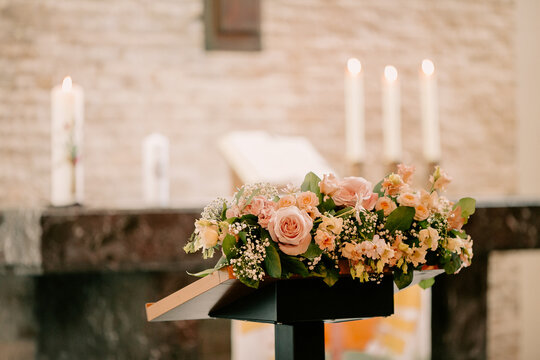 Close up of flower composition on background of Altar of the ancient church with candles and Bible, prepared for wedding ceremony