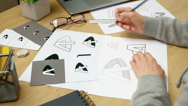 A graphic designer develops a logo for a brand. The illustrator draws sketches on paper.