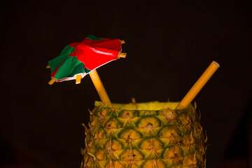 Exotic pineapple in the shape of a drink, with organic straw and mini umbrella
