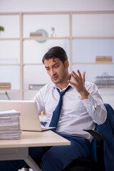 Naklejka premium Young male employee and too much work in the office
