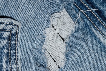 Torn blue denim clothing with pocket seams and stitching. Flat lay worn out jeans isolated section.