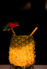 Exotic pineapple in the shape of a drink, with organic straw and mini umbrella