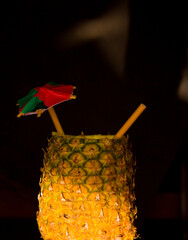 Exotic pineapple in the shape of a drink, with organic straw and mini umbrella