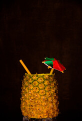 Exotic pineapple in the shape of a drink, with organic straw and mini umbrella