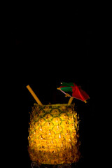 Exotic pineapple in the shape of a drink, with organic straw and mini umbrella